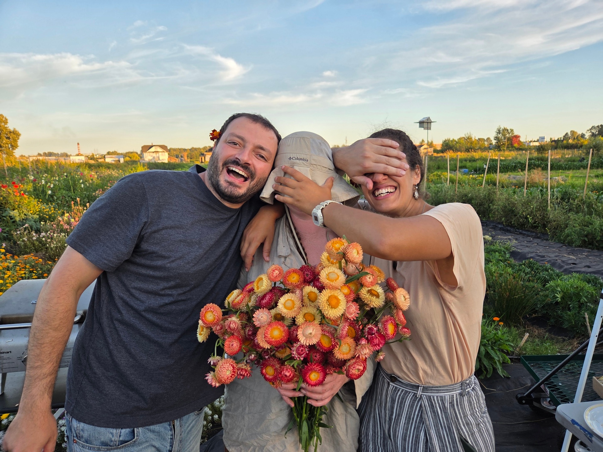Friends laughing in the garden with a bouquet of strawflowers
